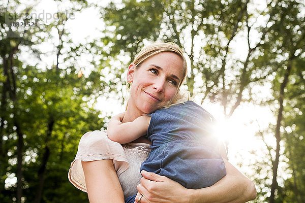 Mittlere erwachsene Frau mit Kleinkind Tochter im sonnigen Park