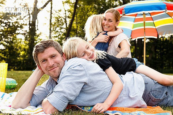 Junge Tochter auf Vater liegend beim Familienpicknick im Park