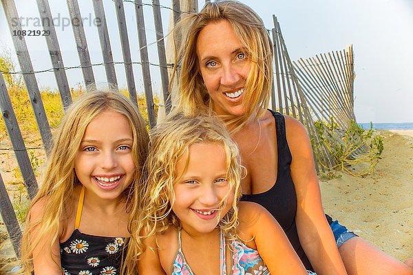 Porträt der blondhaarigen Mutter und zweier Töchter am Strand