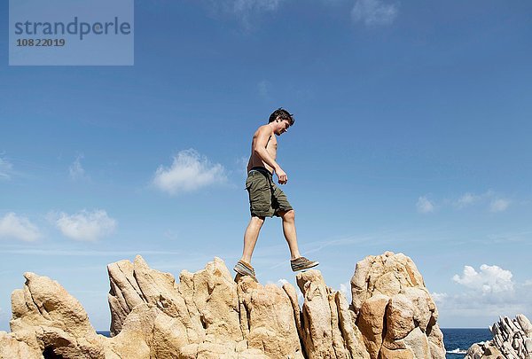 Seitenansicht des jungen Mannes beim Klettern auf Felsen  Costa Paradiso  Sardinien  Italien