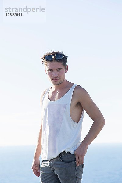 Junger Mann in Weste mit Sonnenbrille auf dem Kopf lächelnd  Capo Caccia  Sardinien  Italien