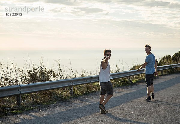 Durchgehende Rückansicht von jungen Männern auf der Straße mit Blick über die Schulter  Alghero  Sardinien  Italien