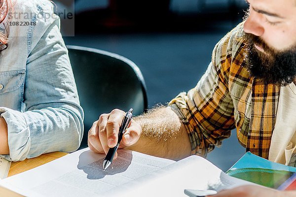 Schnappschuss von männlichen und weiblichen Studenten beim Lesen am Schreibtisch