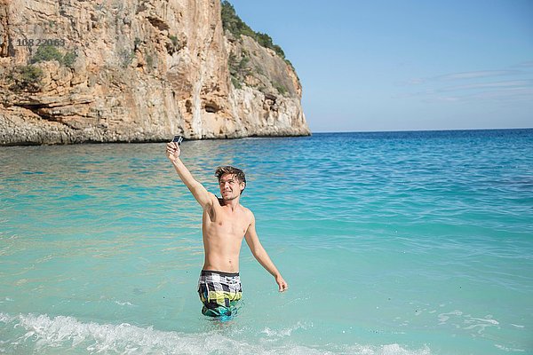 Junger Mann im Meeresarm mit lächelnder Kamera erhoben  Golfo di Orosei  Sardinien  Italien
