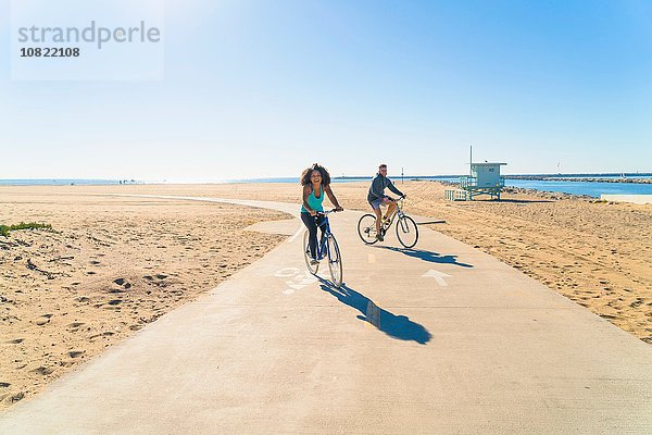 Paar Radfahren entlang des Weges am Strand