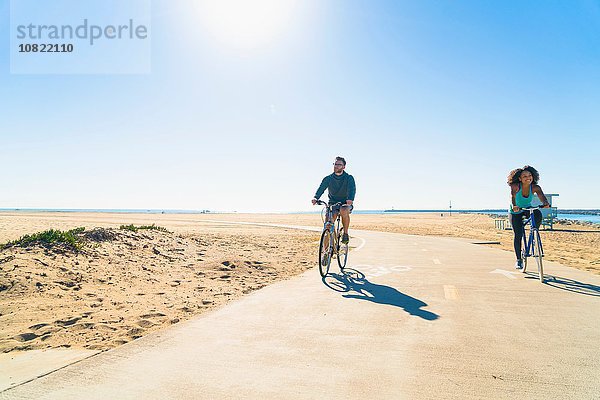 Paar Radfahren entlang des Weges am Strand