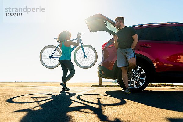 Mittlere erwachsene Frau  die das Fahrrad in den Kofferraum stellt