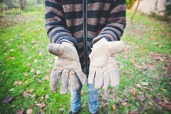 Mittlerer Erwachsener Mann mit gestreifter Strickjacke und Schutzhandschuhen  Hände offen