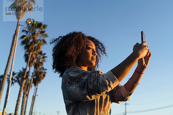 Mittlere erwachsene Frau  Sonnenlicht  fotografieren  Smartphone benutzen