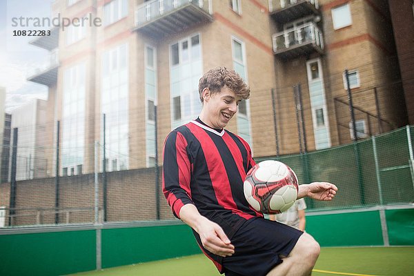 Junger Mann trainiert Fußball auf dem städtischen Fußballplatz