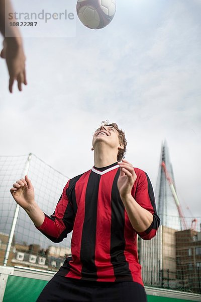 Junger Mann trainiert Fußball auf dem städtischen Fußballplatz