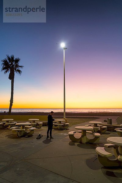Junger Mann  draußen bei Sonnenuntergang  mit Smartphone