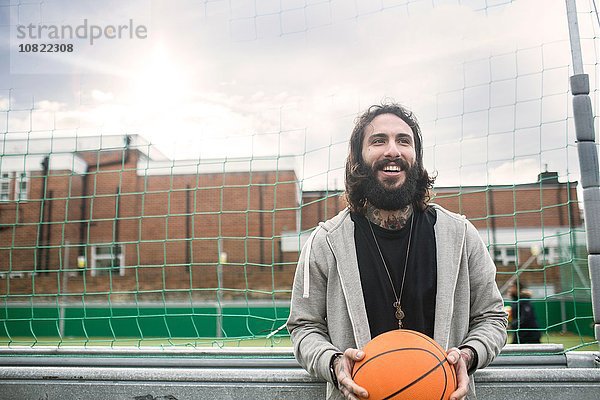 Porträt eines erwachsenen Mannes  der Basketball hält.