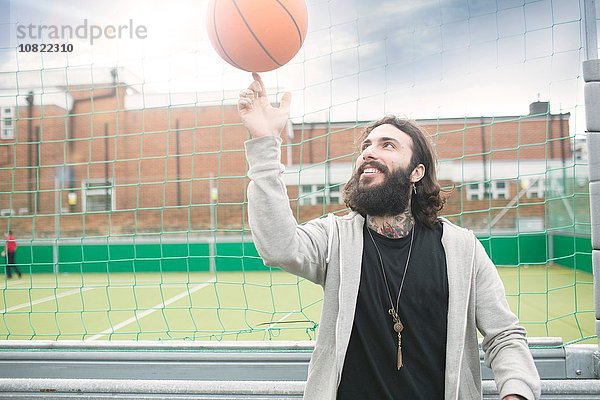 Mittlerer Erwachsener Mann  der Basketball auf dem Finger dreht