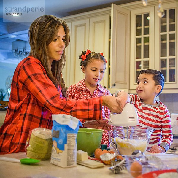 Mutter und Kinder in der Küche mit dem Schneebesen