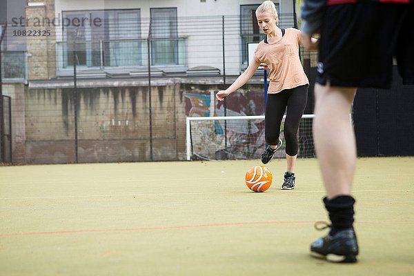 Junge Frau spielt Fußball auf dem Stadtfußballplatz