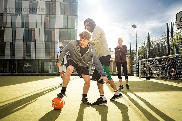 Gruppe von Erwachsenen  die auf dem Stadtfußballplatz Fußball spielen