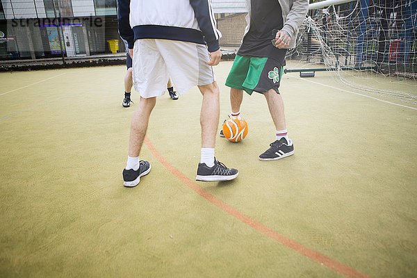 Gruppe von Erwachsenen  die Fußball auf dem städtischen Fußballplatz spielen  niedriger Abschnitt