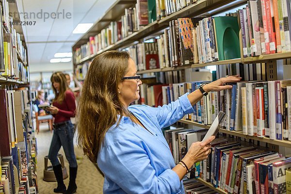 Reife Frau bei der Auswahl von Büchern in der Bibliothek