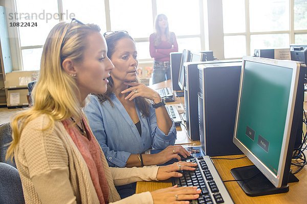 Zwei Frauen suchen Computerdaten für Bücher in der Bibliothek