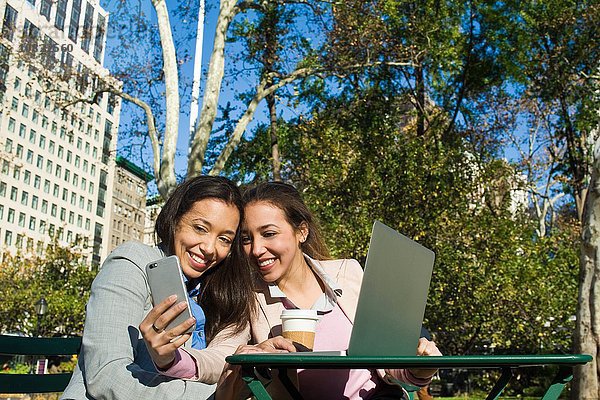 Junge erwachsene weibliche Zwillinge nehmen Smartphone Selfie im Stadtpark