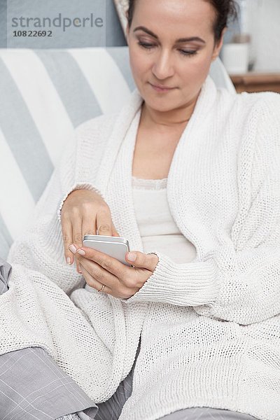 Frau entspannt zu Hause  mit Smartphone