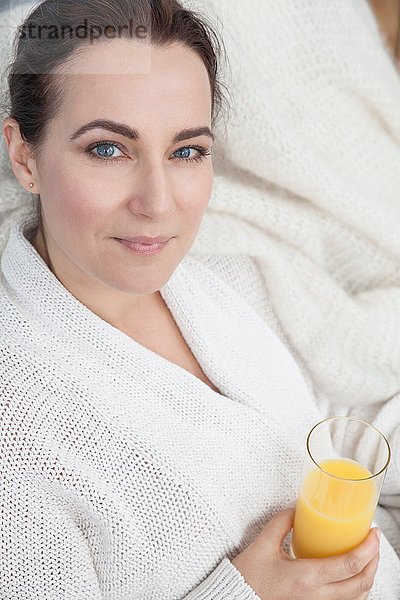 Frau entspannt zu Hause mit einem Glas Orangensaft