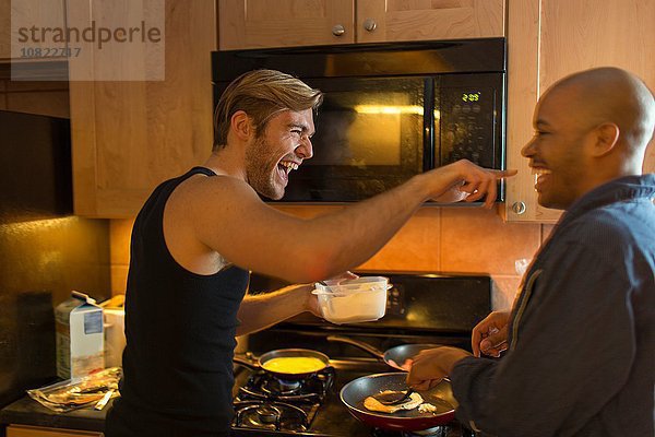 Männliches Paar in der Küche  herumalbern  Frühstück machen