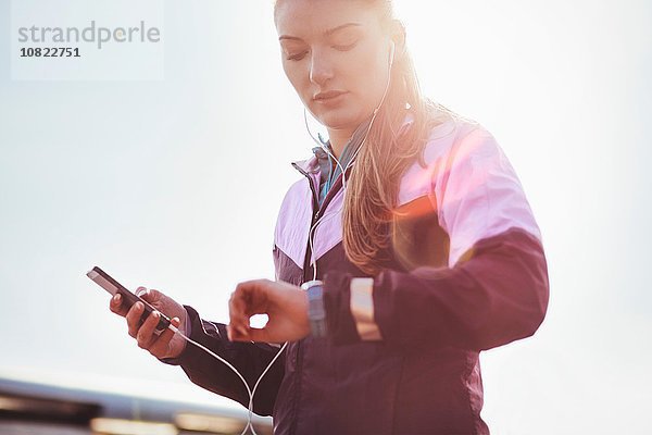 Mittlere erwachsene Läuferin mit Kopfhörer  die die Zeit auf der smartwatch überprüft.