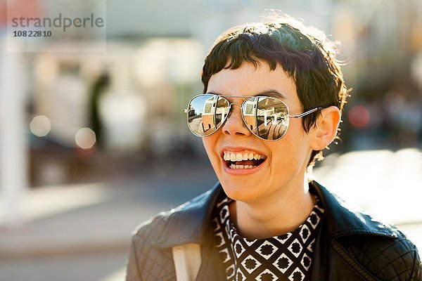 Porträt einer mittleren erwachsenen Frau  im Freien  mit verspiegelter Sonnenbrille