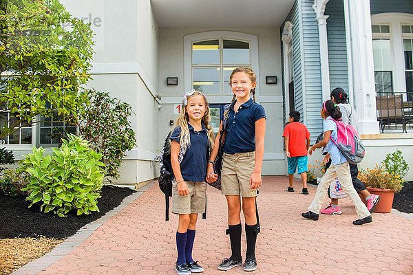 Glückliche Mädchen stehen vor der Schule