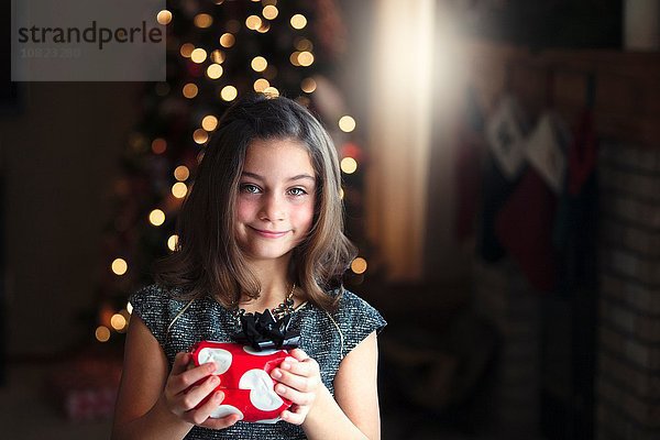 Porträt eines Mädchens vor dem Weihnachtsbaum mit einem lächelnden Blick auf die Kamera