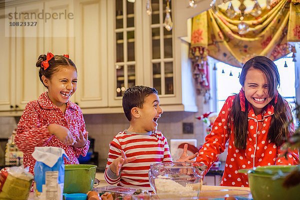 Kinder im Pyjama beim Backen in der Küche  lachend