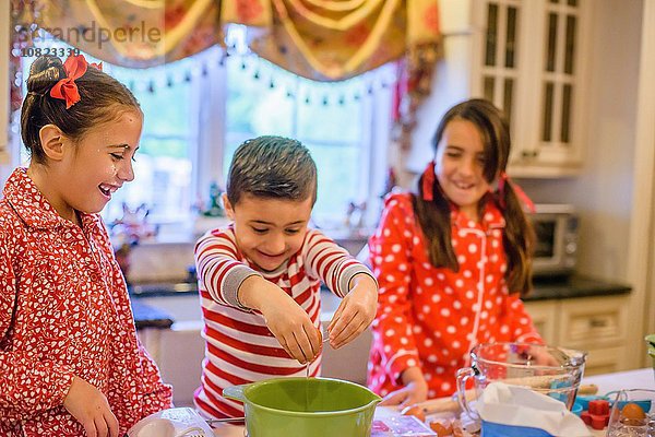 Kinder in der Küche mit Pyjamas  die Eier in die Rührschüssel knallen  lächelnd