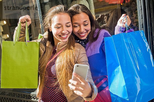 Junge erwachsene Zwillinge in der Stadt nehmen Smartphone Selfie mit Einkaufstüten