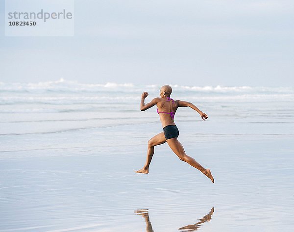 Frau im Bikini sprinten am Strand
