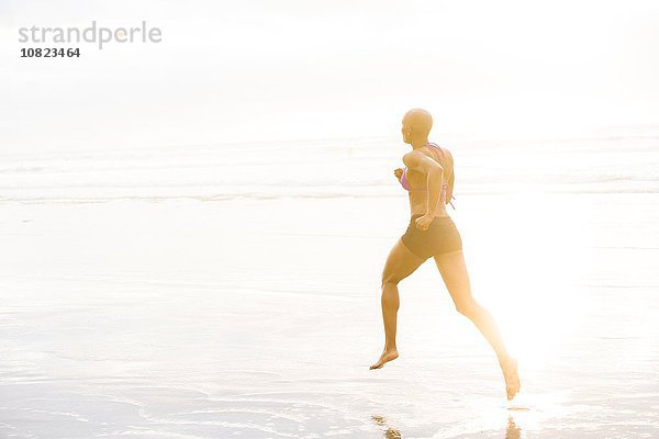 Frau im Bikini joggen am Strand