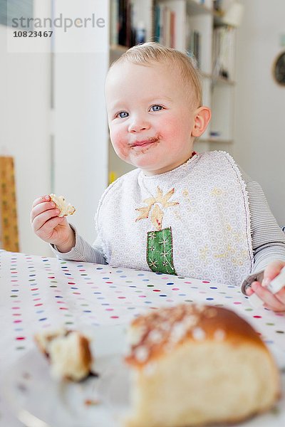 Weibliches Kleinkind beim Brotessen am Küchentisch
