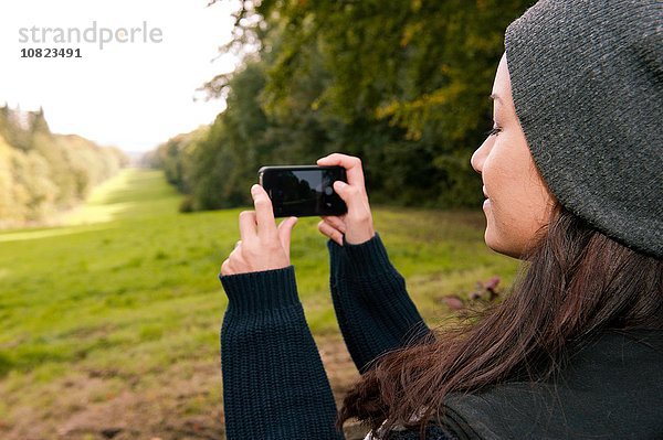 Junge Frau fotografiert Feld auf Smartphone