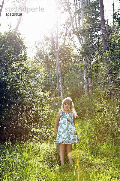 Mädchen steht gegen Baum im Wald