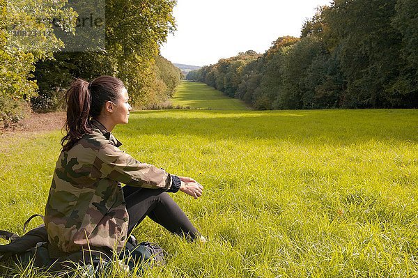 Junge Frau auf dem Feld sitzend mit Blick auf die Landschaft  Great Missenden  Buckinghamshire  U.K.