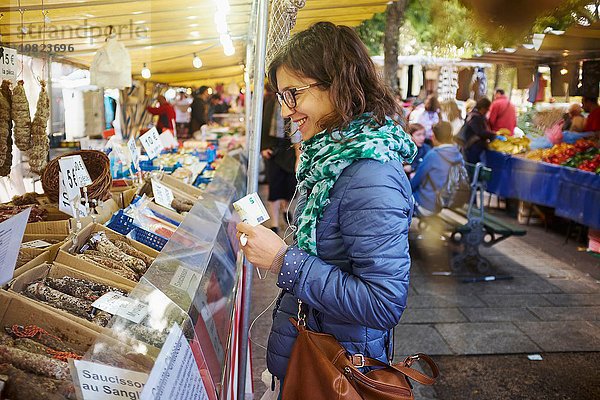 Junge Frau kauft frische Lebensmittel am Marktstand