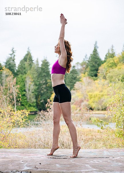 Seitenansicht der jungen Frau beim Yoga am Waldseeufer