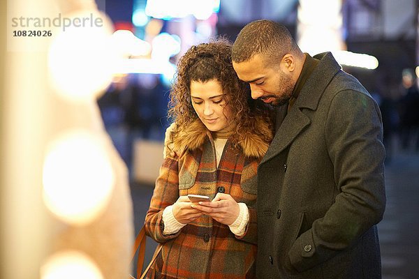 Paar schaut auf Smartphone  im Freien  nachts