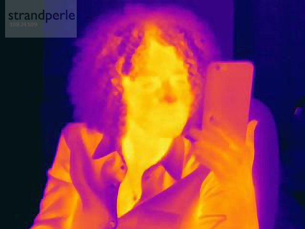 Frau mit lockigem Haar mit Smartphone  Wärmebild