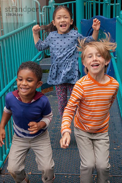 Mädchen und Jungen laufen auf dem Spielplatz Klettergerüst