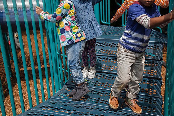 Schnappschuss von vier Jungen und Mädchen  die auf einem Klettergerüst auf dem Spielplatz spielen.