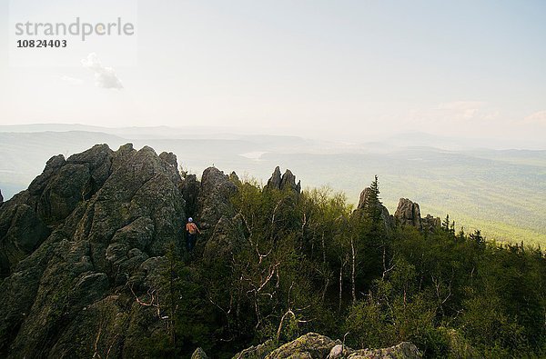 Rückansicht des jugendlichen Wanderers beim Klettern in einer schroffen Felsformation  Russland