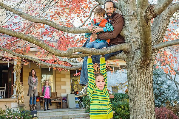 Vater und Kinder klettern Baum im Garten