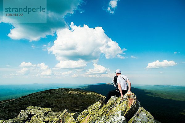 Junger Wanderer auf Felsen sitzend mit Blick auf die Landschaft  Russland